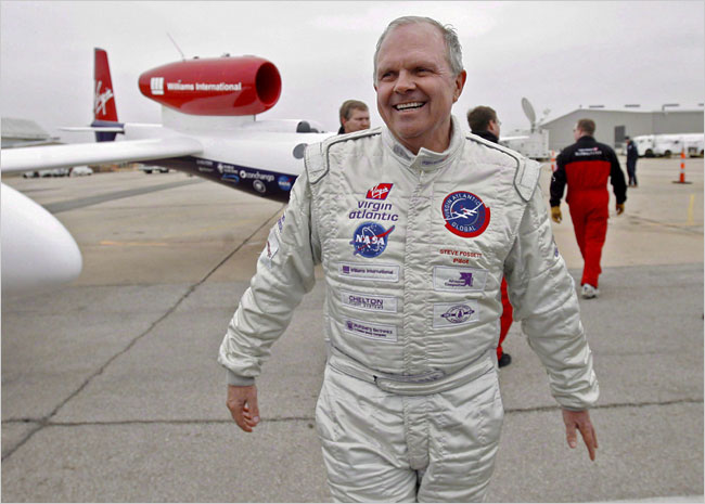 Steve Fossett walks in front of an aircraft, wearing white pilot's suit adorned with Virgin Atlantic and NASA logos. Fossett is an Eagle Scout.